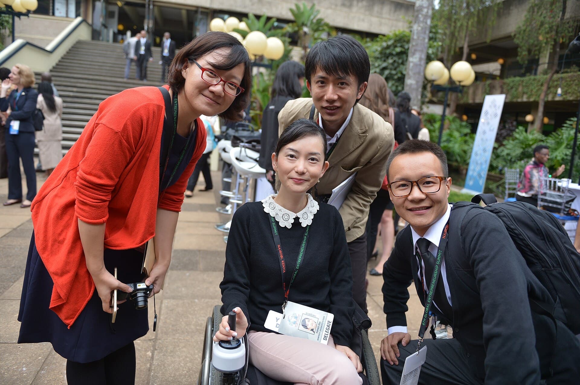 Four smiling delegates at an entrepreneurship summit, one of them using a wheelchair